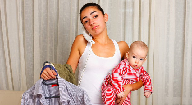 mom holding baby and ironing