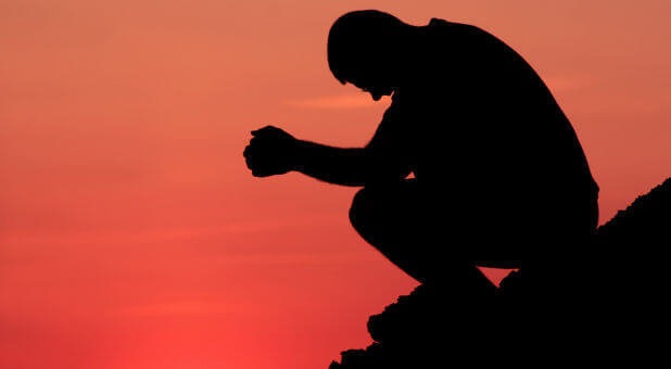 man praying at sunset