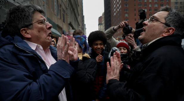 A supporter of President Donald Trump (R) argues with a protester as New York City high school students look on during a protest against Trump's immigration policies in lower Manhattan, New York.