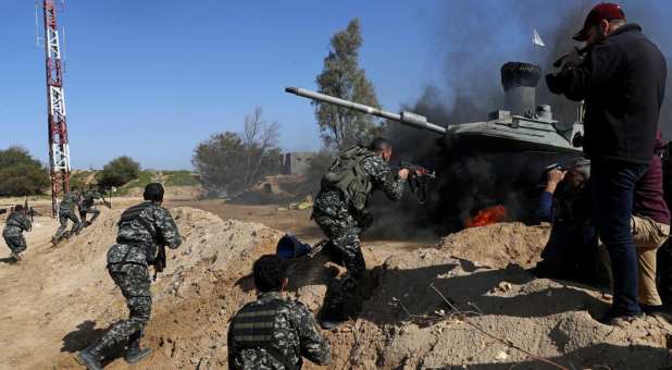 Palestinian actors dressed as militants attack a replica of Israeli tank while a crew from the Hamas-run al-Aqsa satellite channel shoots for a 30-episode series, titled “Fist of the Free,” in Beit Lahiya, northern Gaza Strip, Thursday, Feb. 3, 2022. The series is the latest production by the media arm of Hamas and presents the Hamas fighters as scrappy heroes outwitting a better-armed Israeli military.